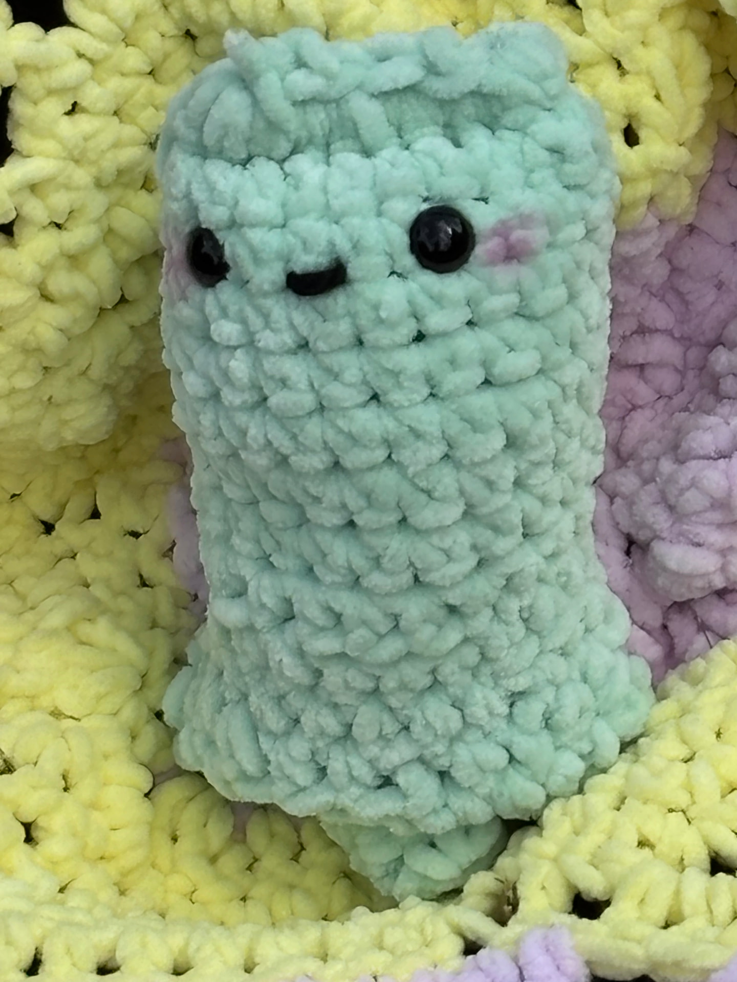 Mint green chunky crochet pocket plush with black eyes and a smile