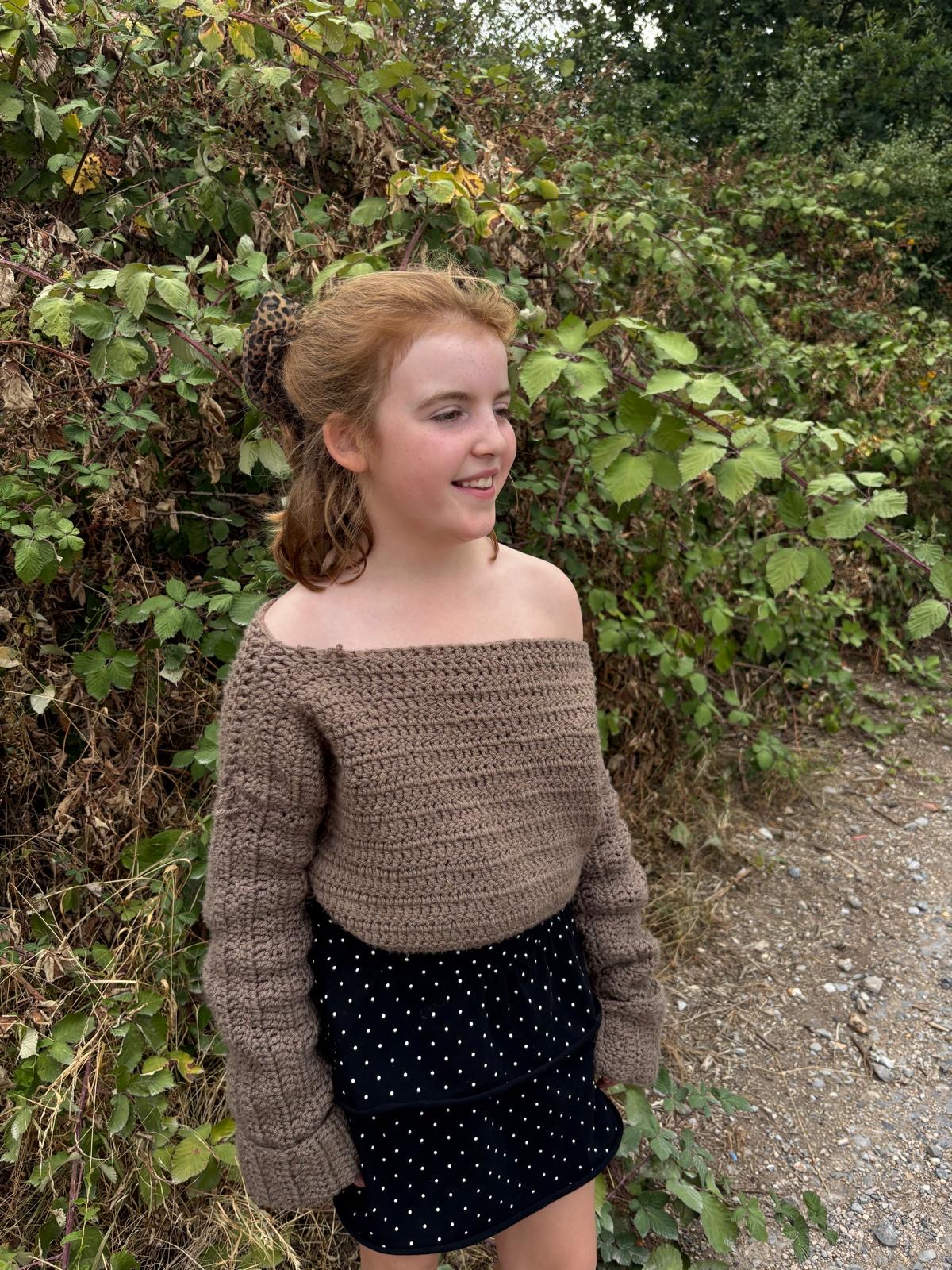 Girl wearing a soft taupe off-the-shoulder crochet jumper with long sleeves
